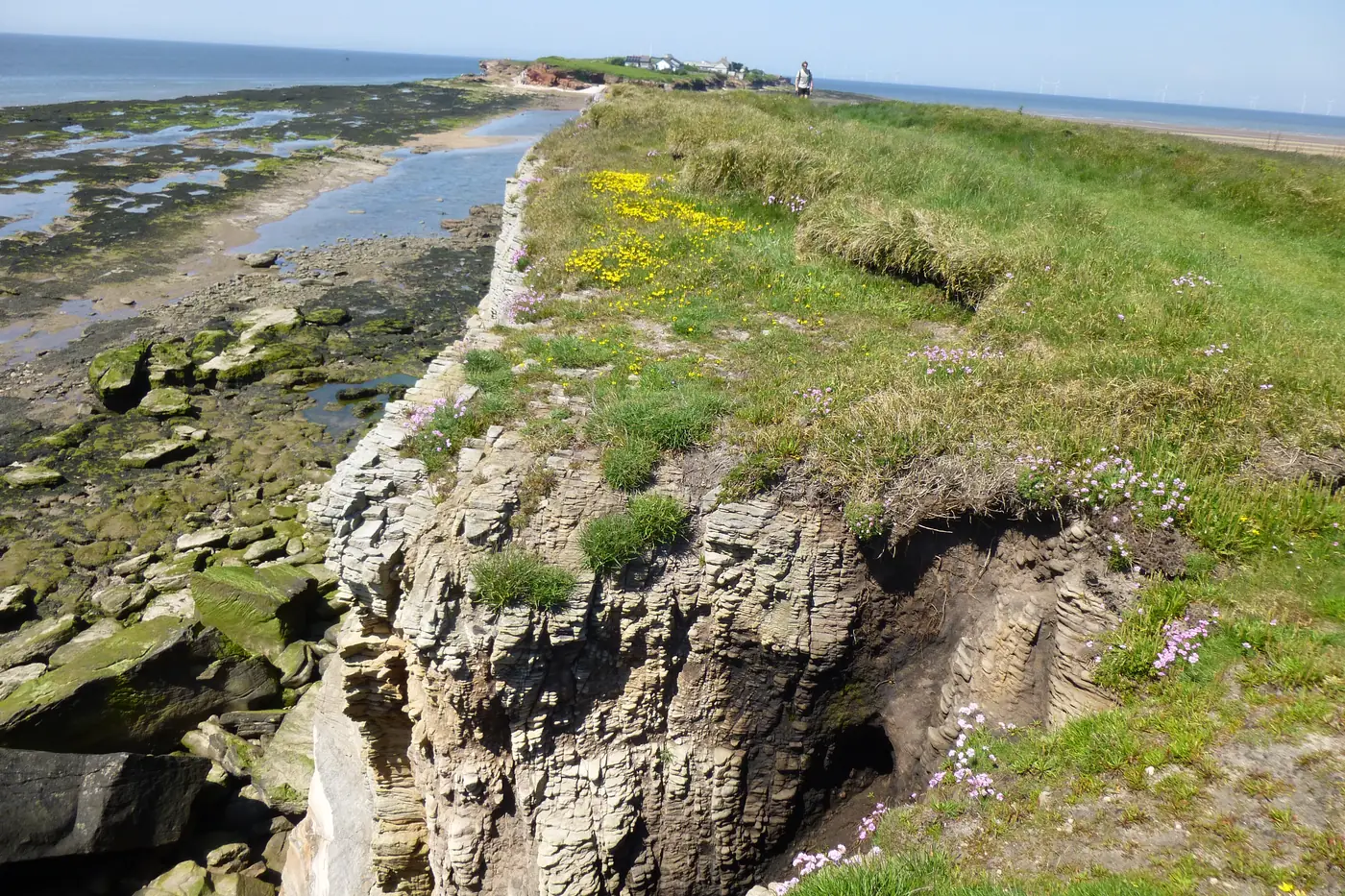 The rocky shore of Middle Eye at low tide, with a channel of water still lying between it and Hilbre Island beyond